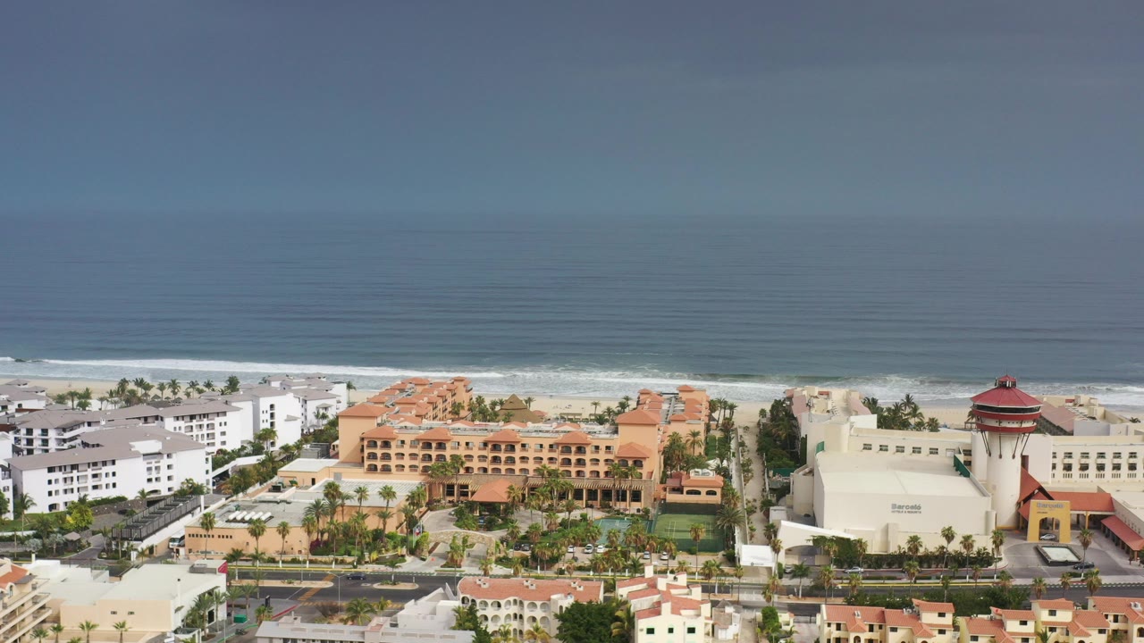 Aerial view of beachfront buildings, road, beach, and ocean horizon.