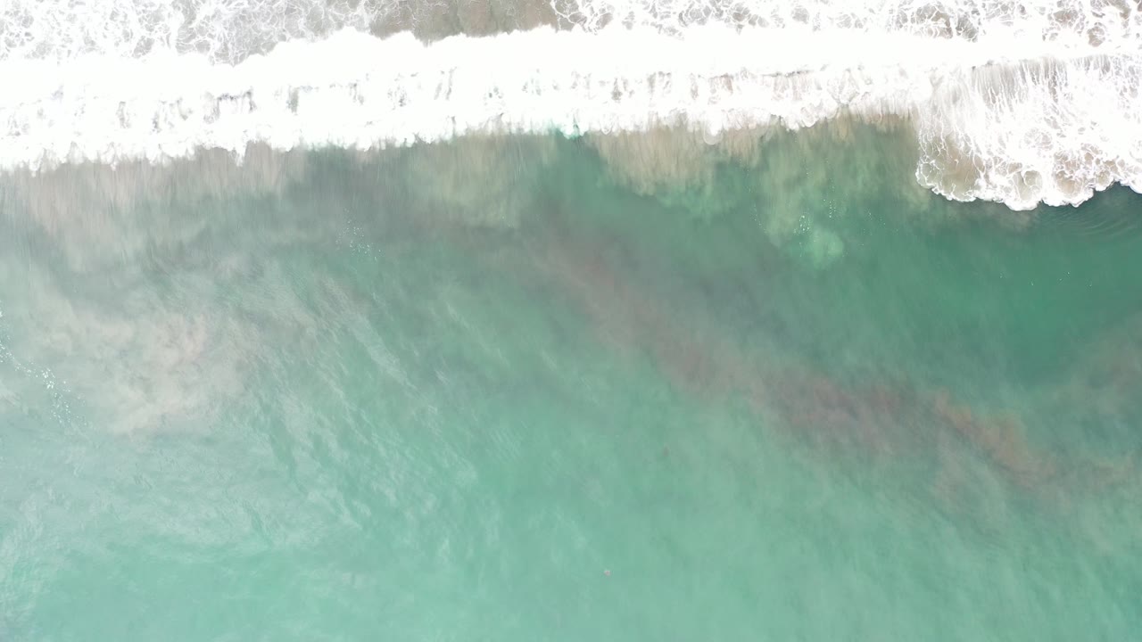 Overhead green ocean water with white surf foam at the top edge.