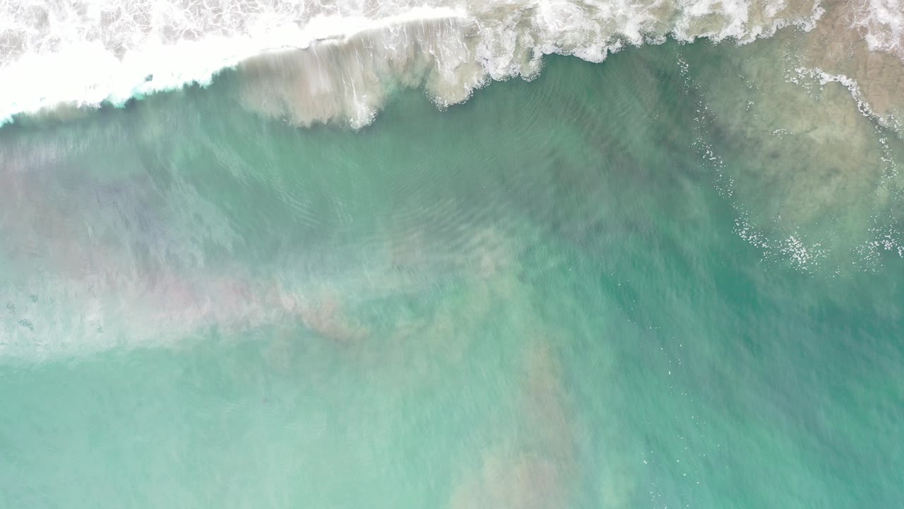 Overhead turquoise surf with white foam at the top of frame.