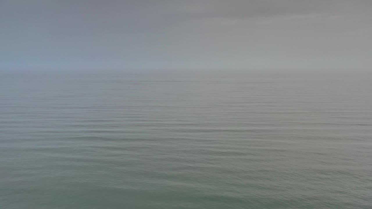 Muted ocean surface with soft distant horizon.