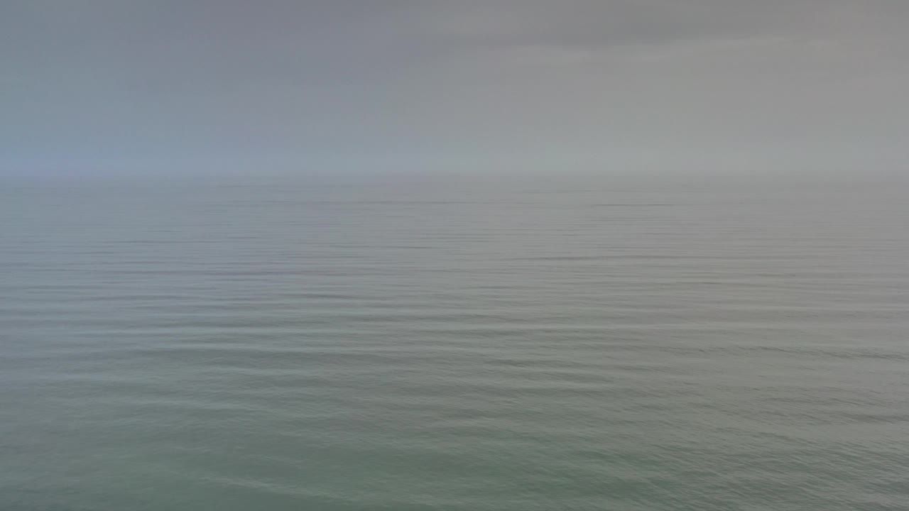 Empty cloudy seascape with muted blue-gray light.