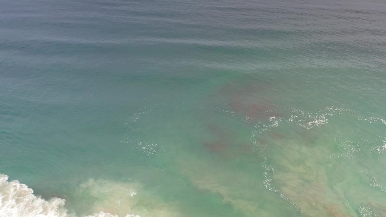 Turquoise water with white surf beginning to push in from below.
