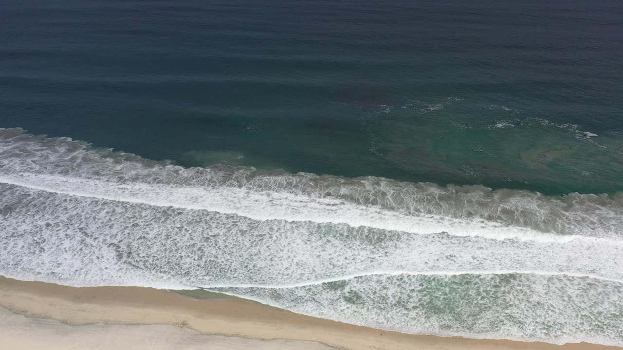 Ocean waves rolling toward a narrow beach strip