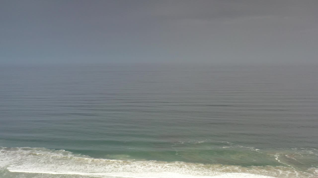 Aerial view of breaking waves under a hazy sky