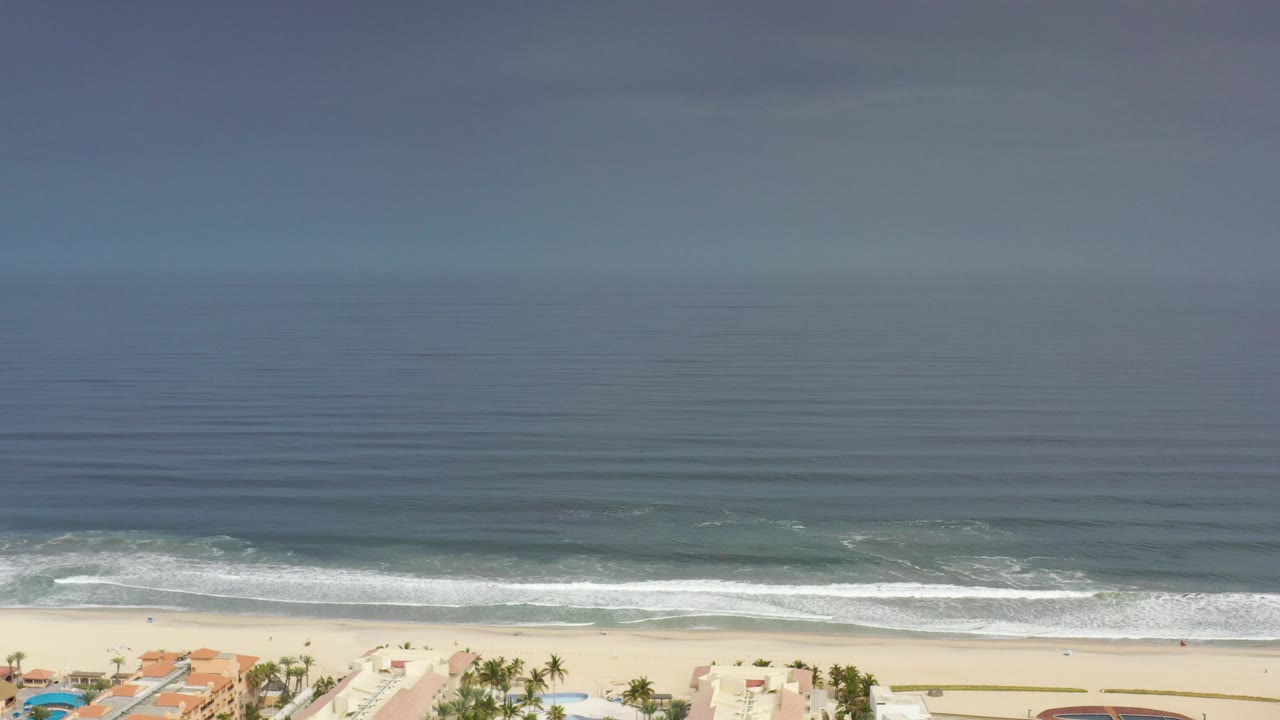 Aerial view of ocean waves reaching a sandy beach.