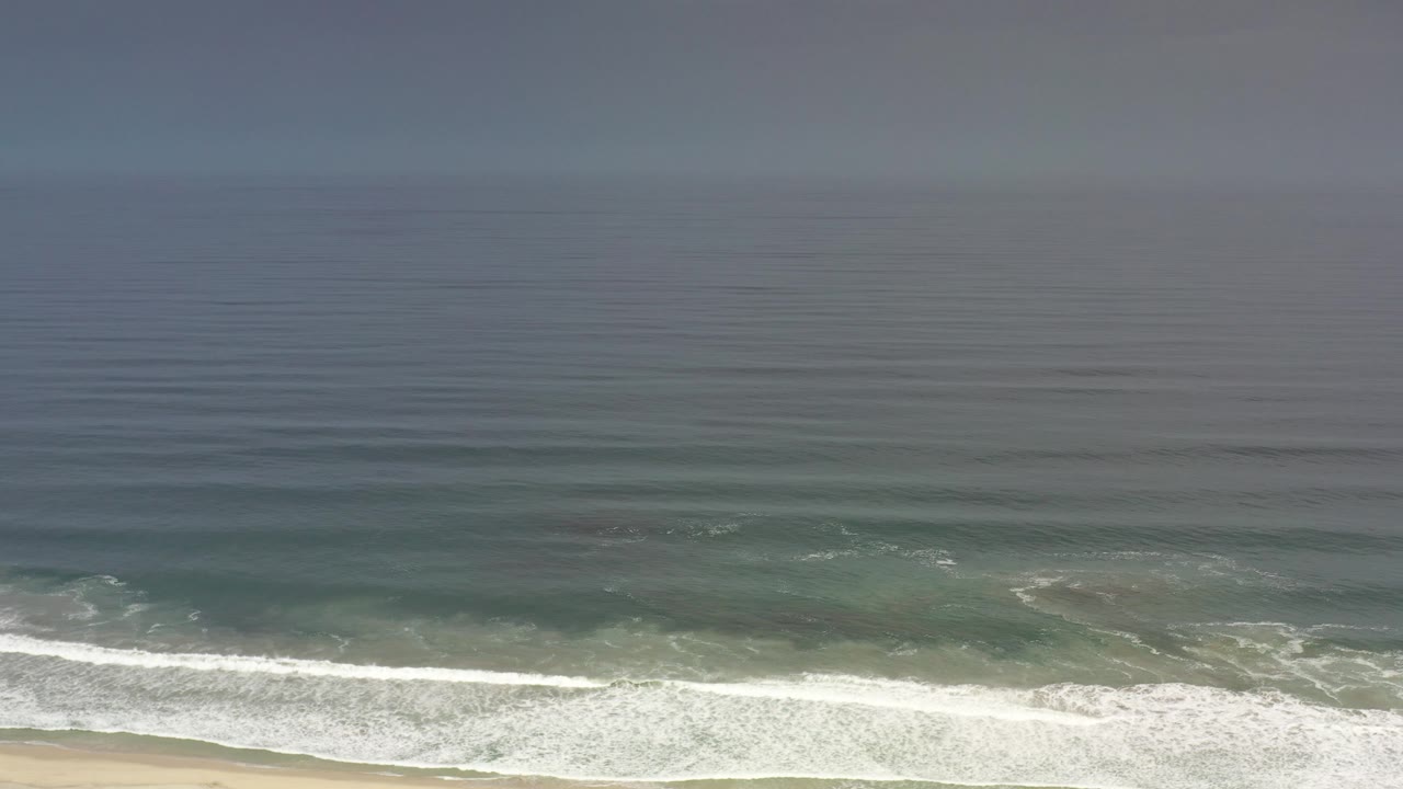Foamy ocean waves spread across the shallow water near shore.