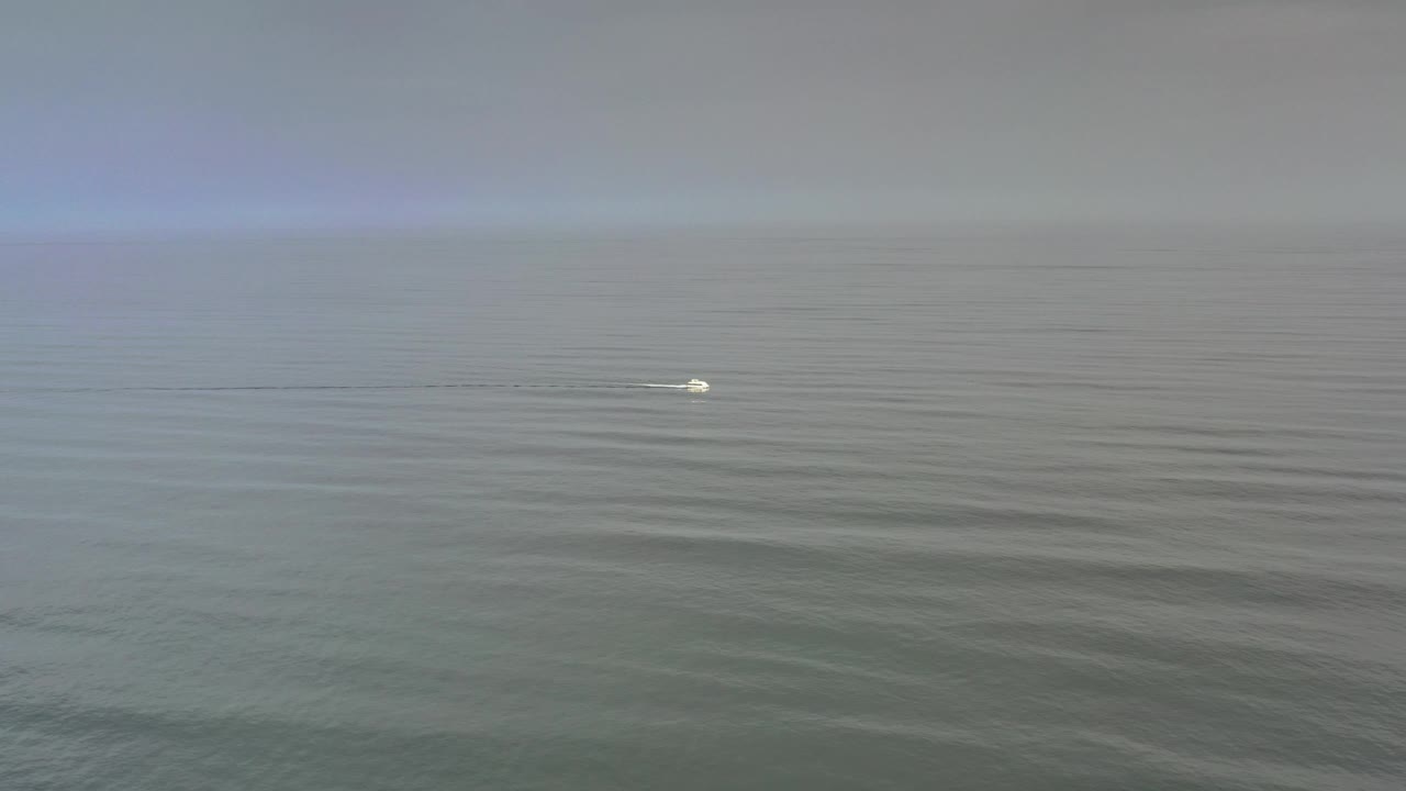 Cloudy ocean horizon with a small white object floating on calm water.