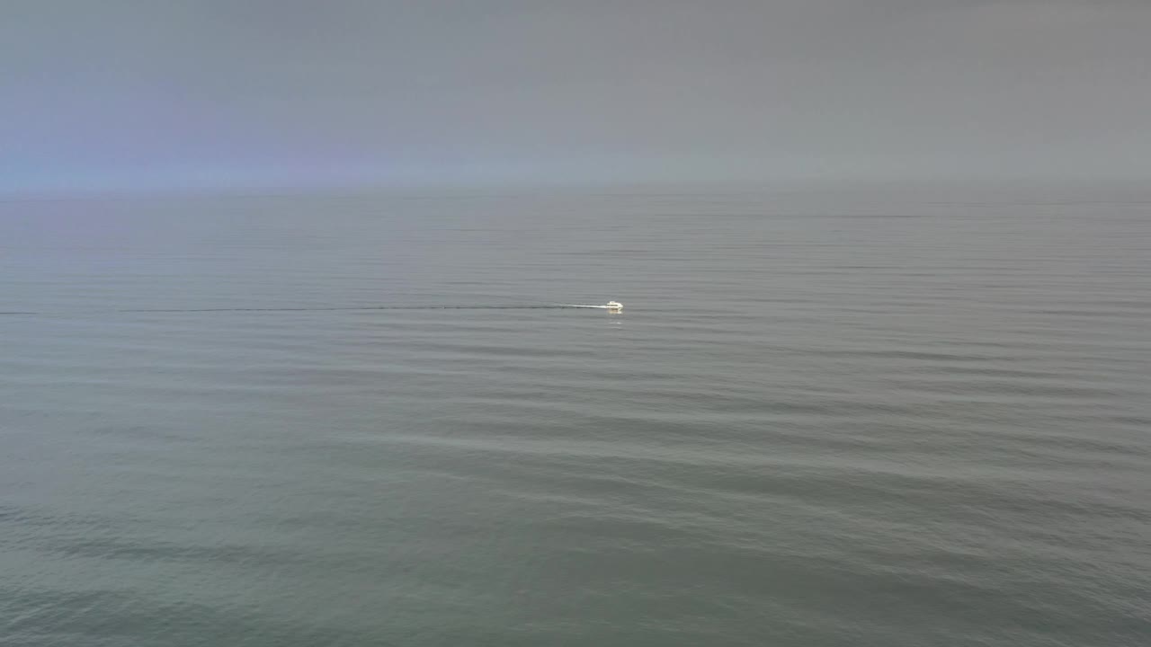 Los Cabos water fills the frame one second in, with soft ripples, pale sky above the horizon, a tiny white mark near the surface, and no visible people.