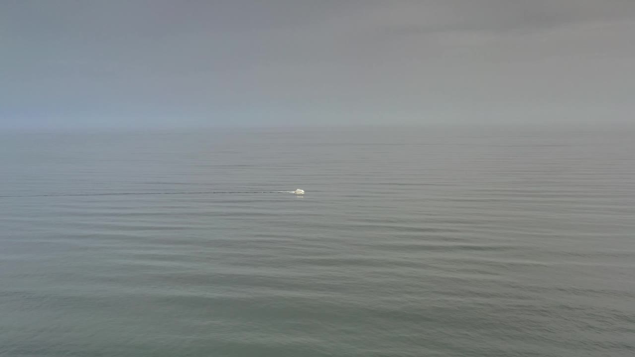 One second into the Los Cabos footage, the small white object remains distant on softly rippled water, with a muted gray sky and no visible people.