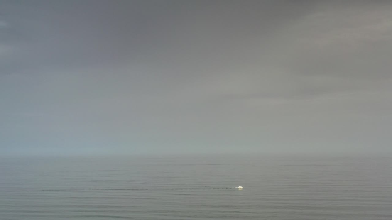 Wide Los Cabos ocean view at the start of the clip, with a gray sky above calm rippled water and no visible people.