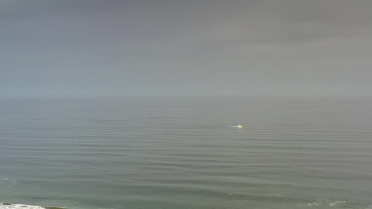 At 0:00 in Los Cabos, Mexico, a small blurry white object sits on muted ocean water below a soft horizon, with no visible people.