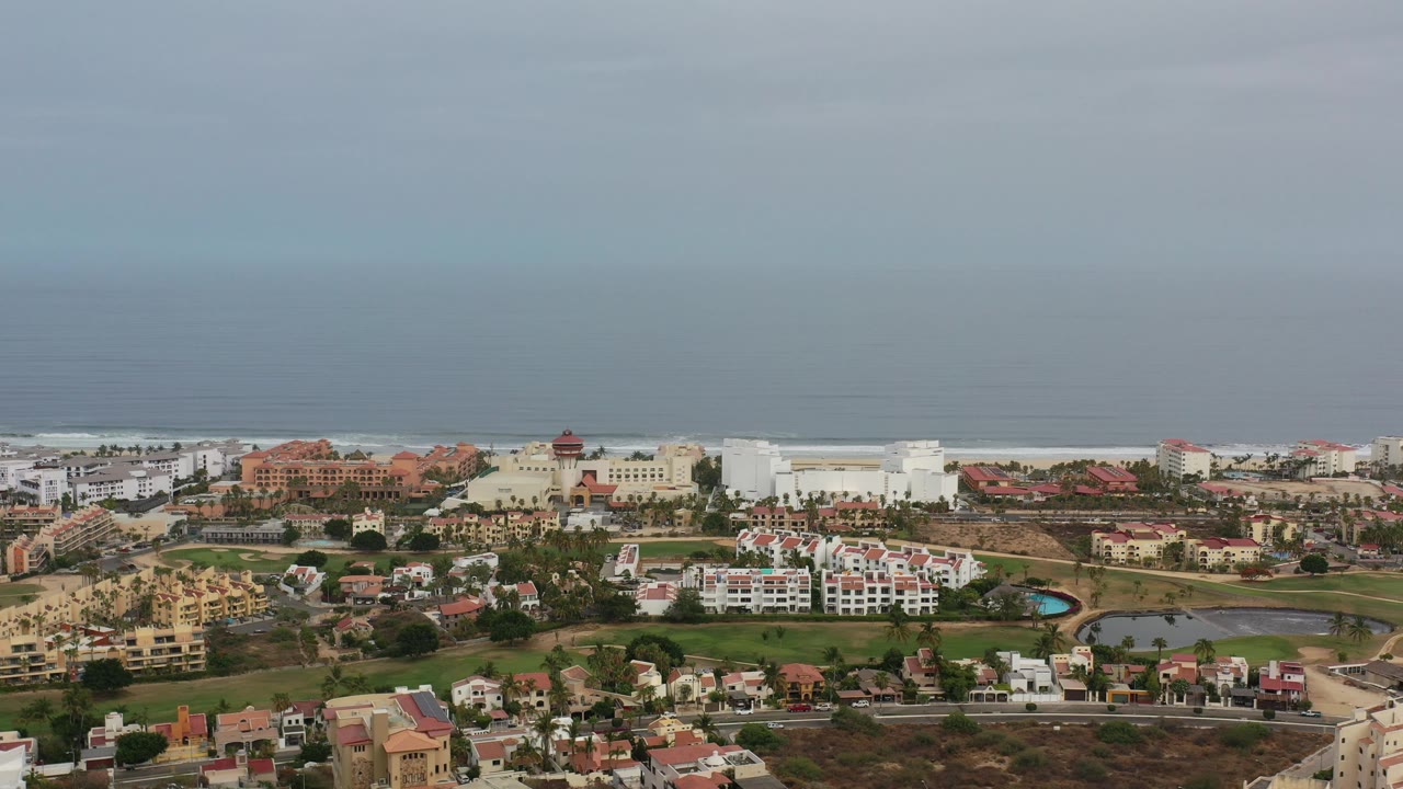 Coastal Los Cabos panorama with buildings, roads, and ocean horizon.