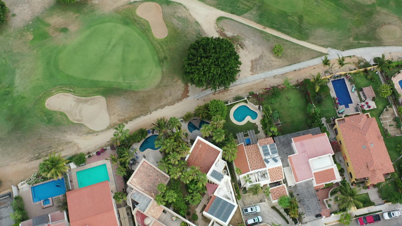 Top-down shot of houses near a golf green and bunker.