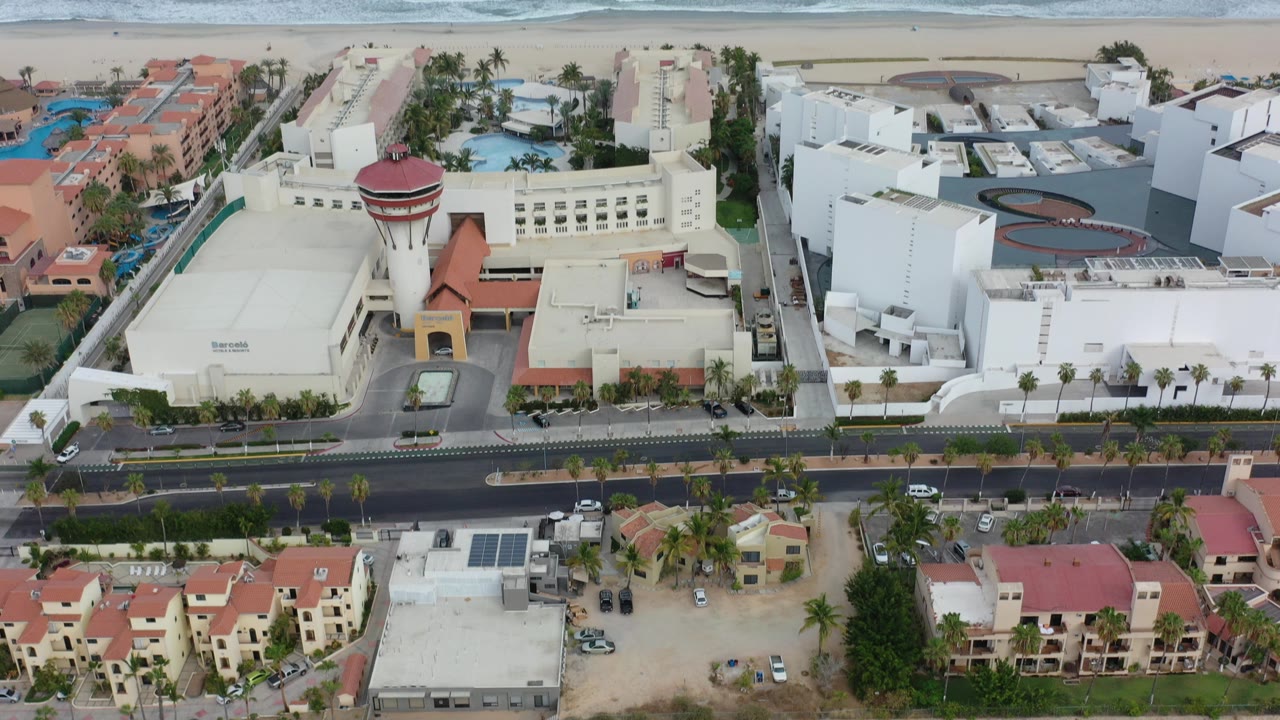 Aerial view of coastal buildings beside a sandy beach and ocean.