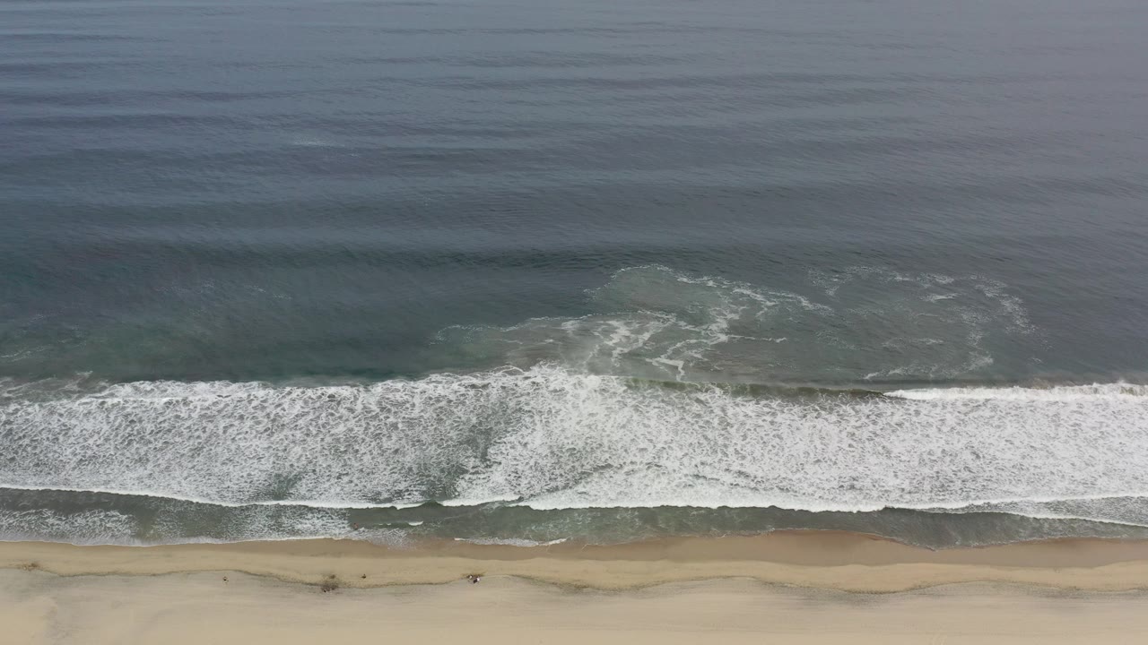 Overhead surf line reaching a sandy beach.