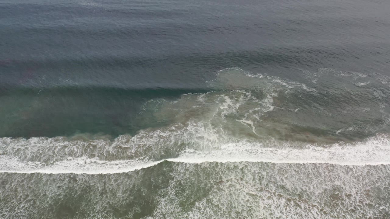 White surf line across green coastal water.