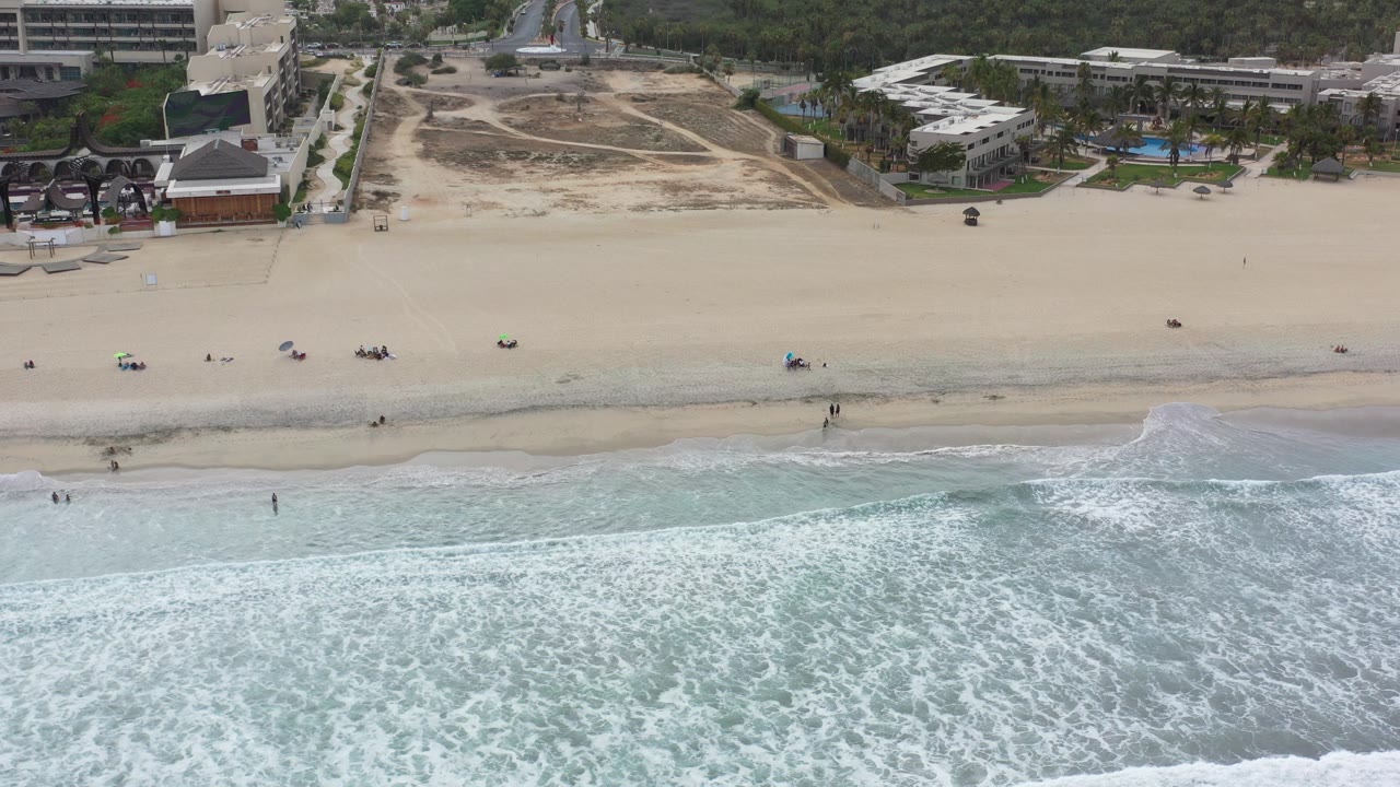 Aerial view of surf washing toward a wide sandy beach.