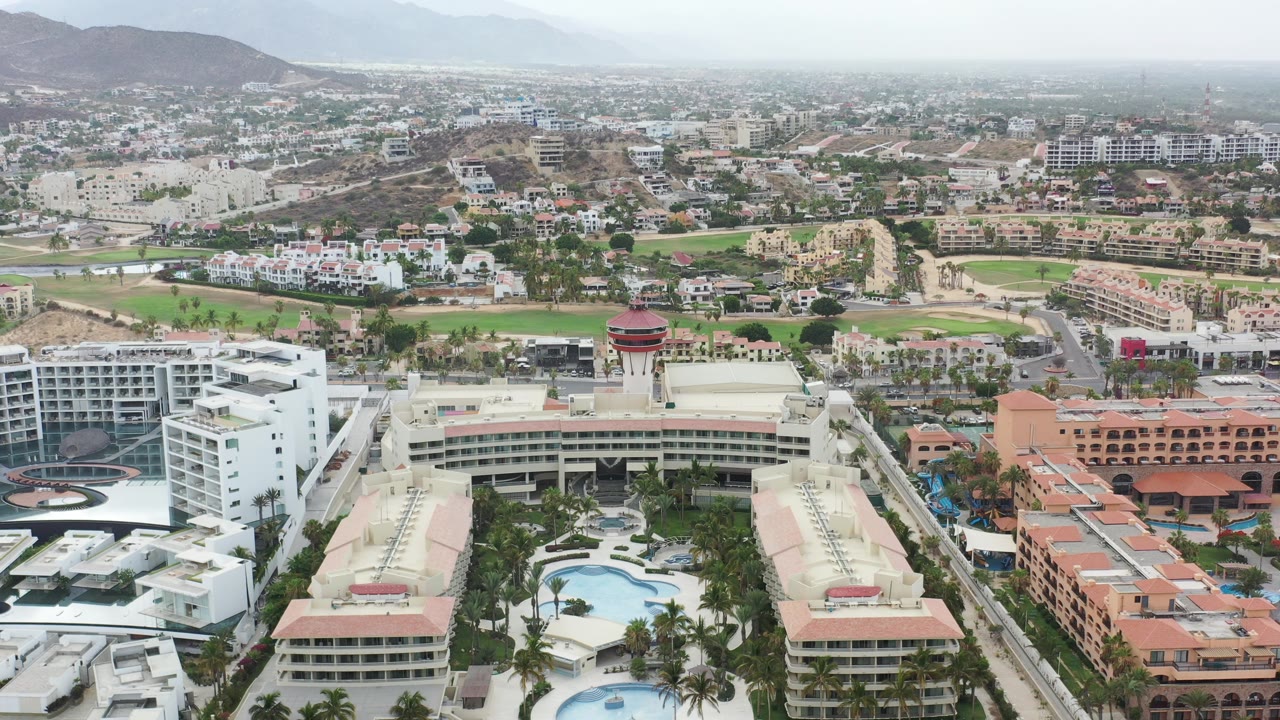 Aerial view of high-rise buildings, pools, roads, and distant hills.