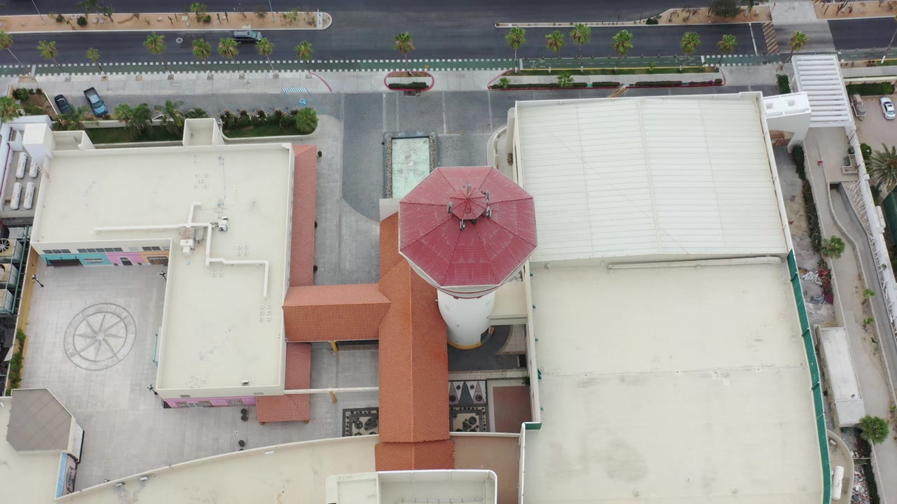 Overhead view of tan rooftops and a red octagonal roof beside a road.