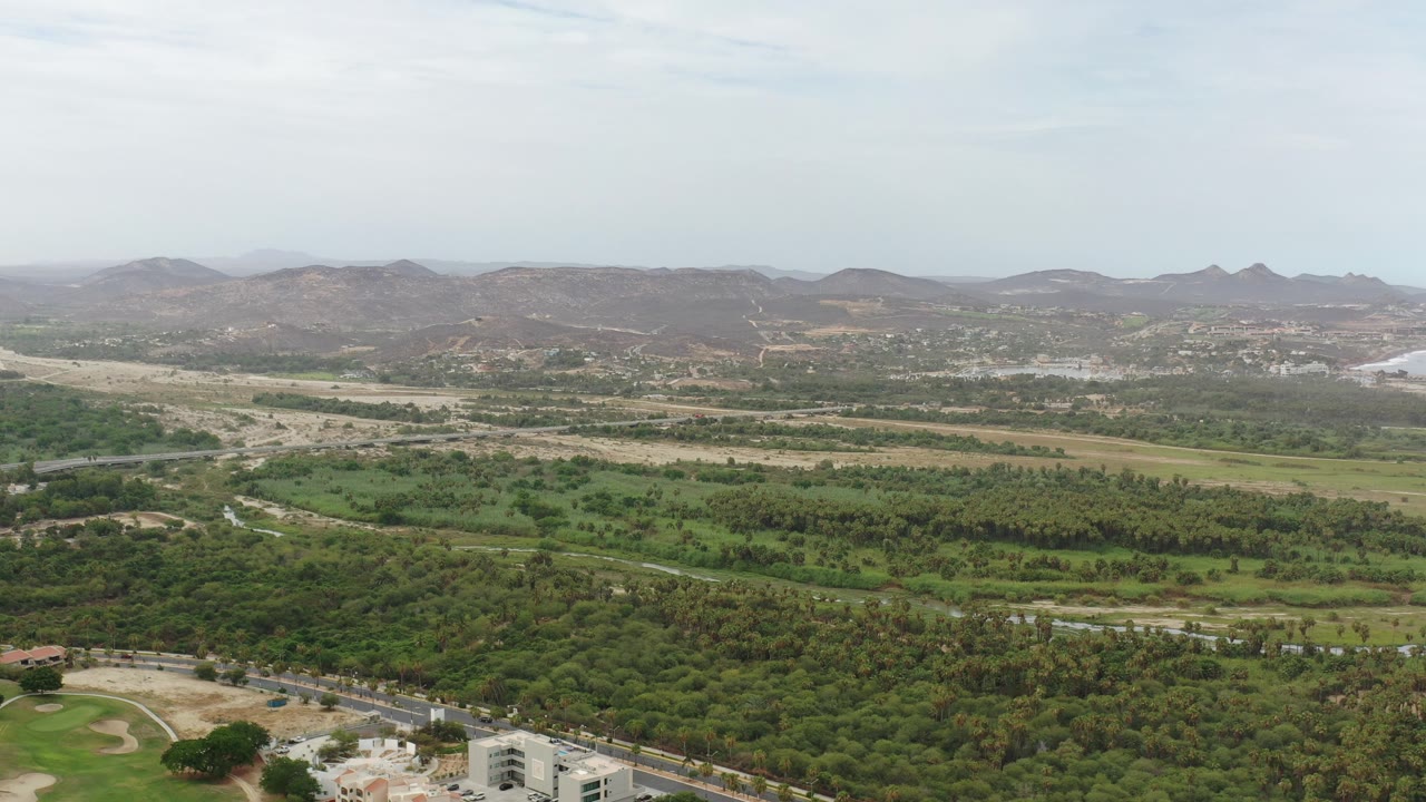 Aerial view of green countryside, roads, and distant hills.