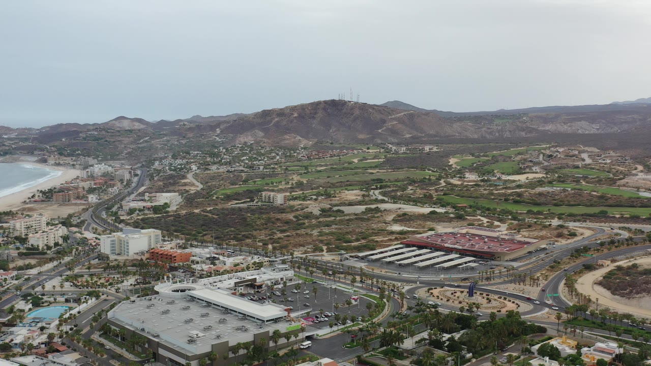 High view across beachfront city toward hills under hazy sky.