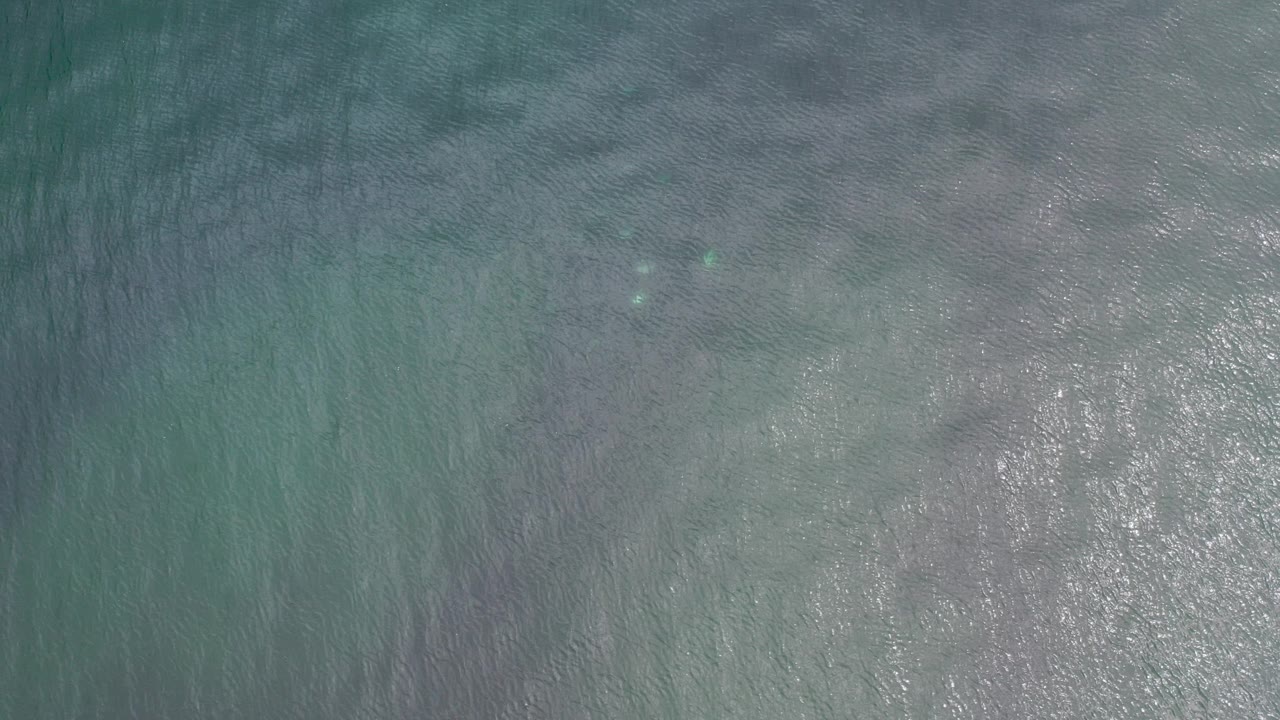 Overhead view of teal and gray ocean water in Los Cabos, Mexico, with scattered sun glints and no visible people.