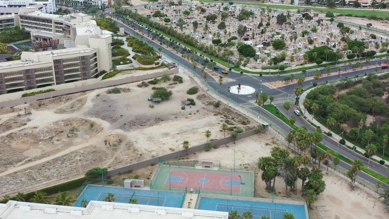 Aerial view of roads, buildings, sports courts, palms, and dry lots.
