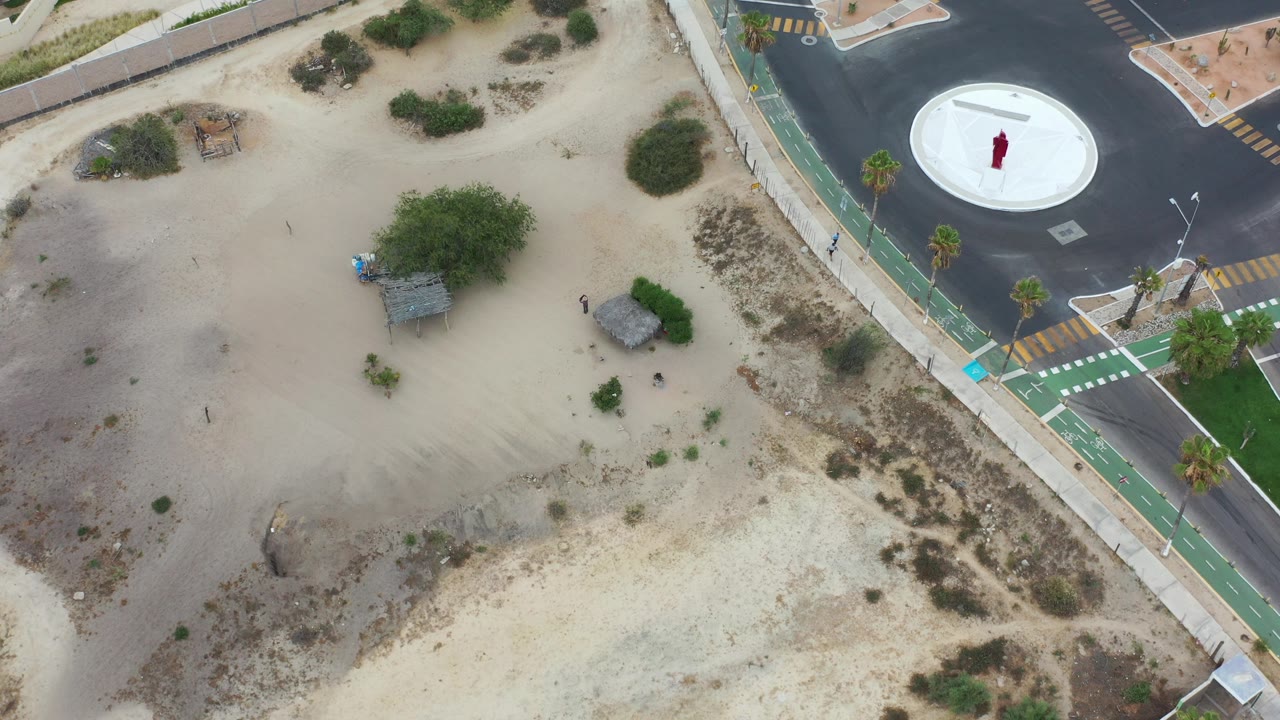 Overhead view of sandy ground beside a road and bike lane.