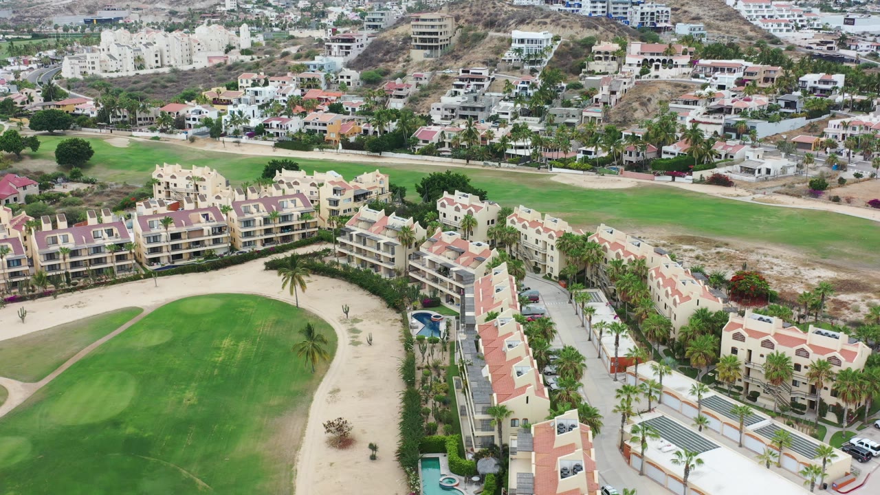 Aerial view of villas and apartments beside a green golf course.