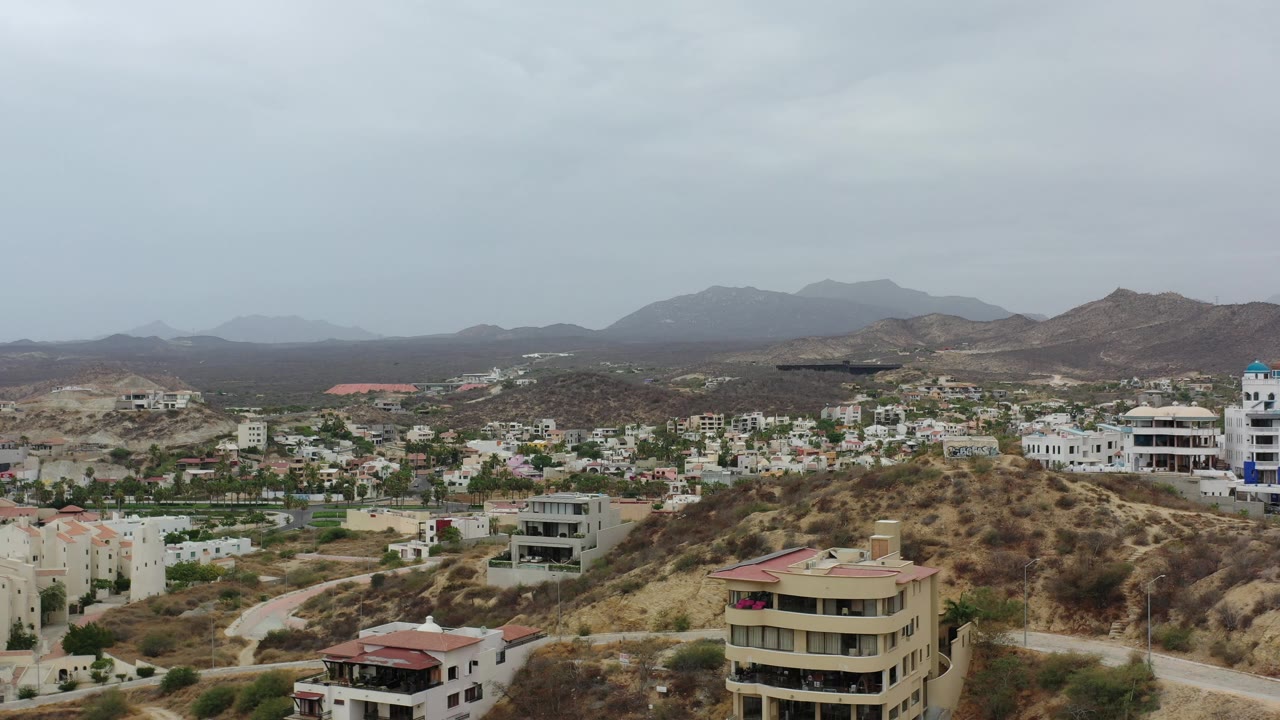 Residential Los Cabos hillside with low-rise buildings and brown mountains.