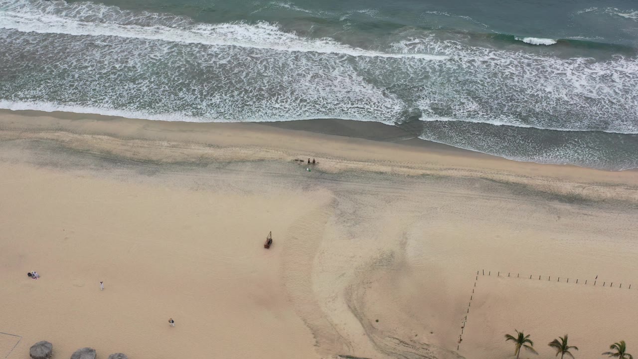 Overhead surf and sandy beach from a drone view.