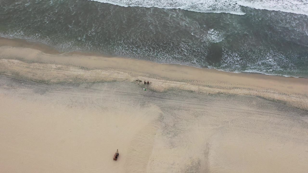 Aerial view in Los Cabos showing a narrow foam band along the waterline and open pale sand below, with no visible people.