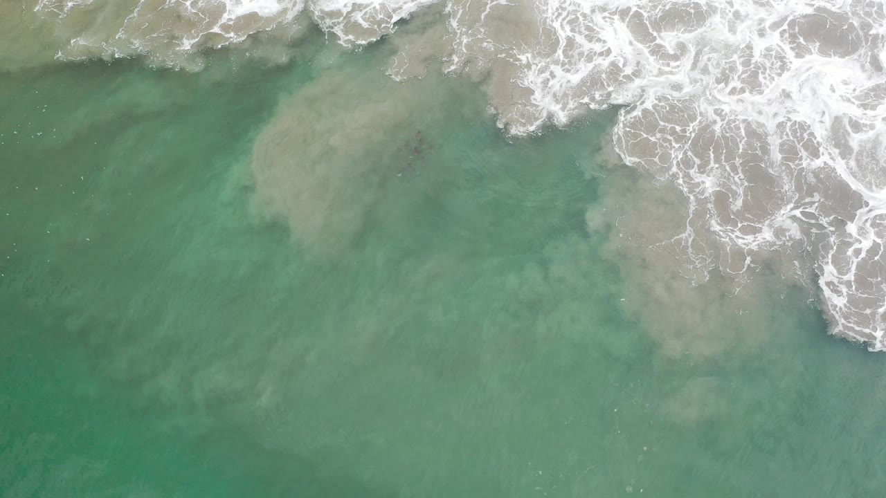 Overhead view of aqua water and white breaking surf over sandy shallows in Los Cabos, Mexico, with no visible people.