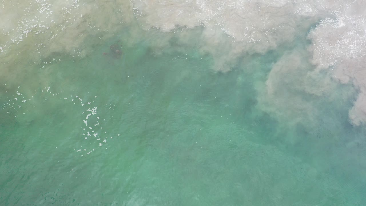 Overhead turquoise seawater with white foam along the top edge