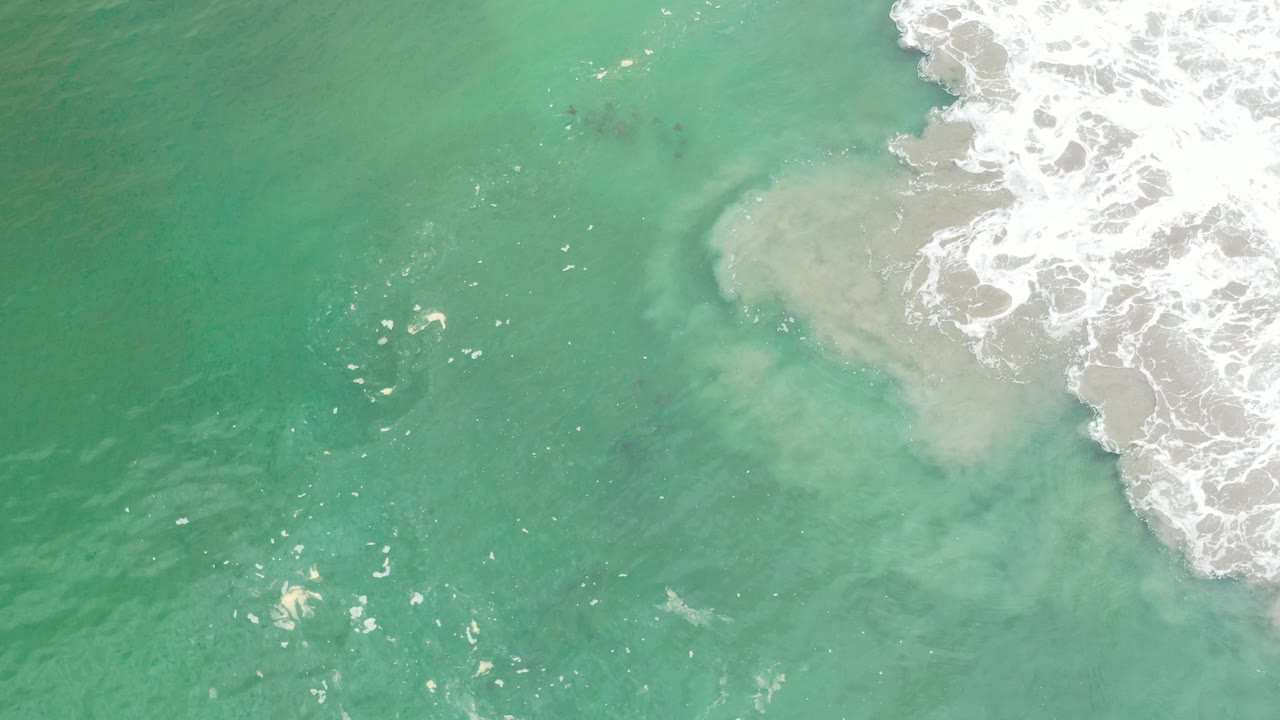 Overhead turquoise water with white surf entering from the upper right.