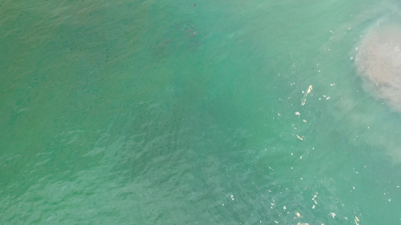 Overhead ocean surface with foam at top right