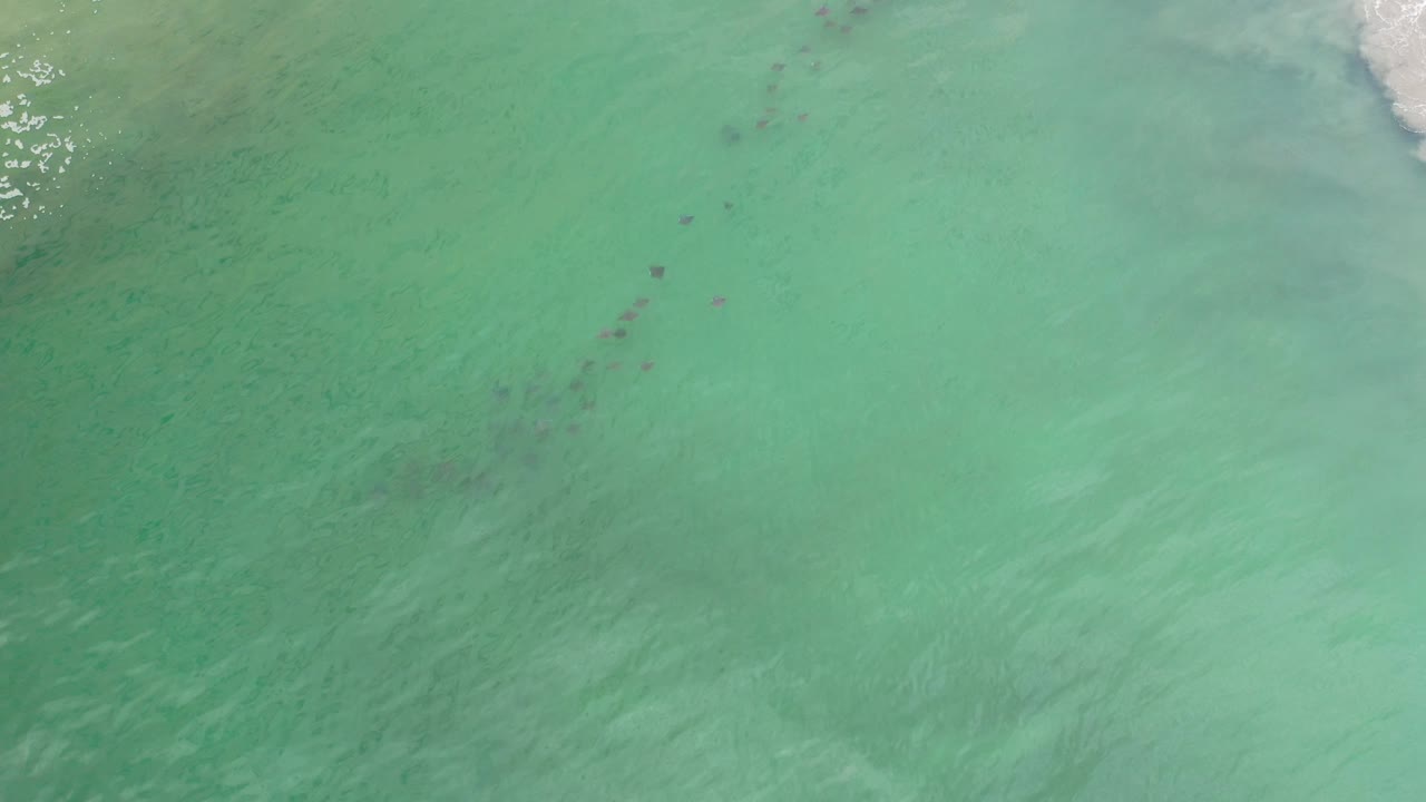 Turquoise-green water with dark patches and a small area of foam near the top.
