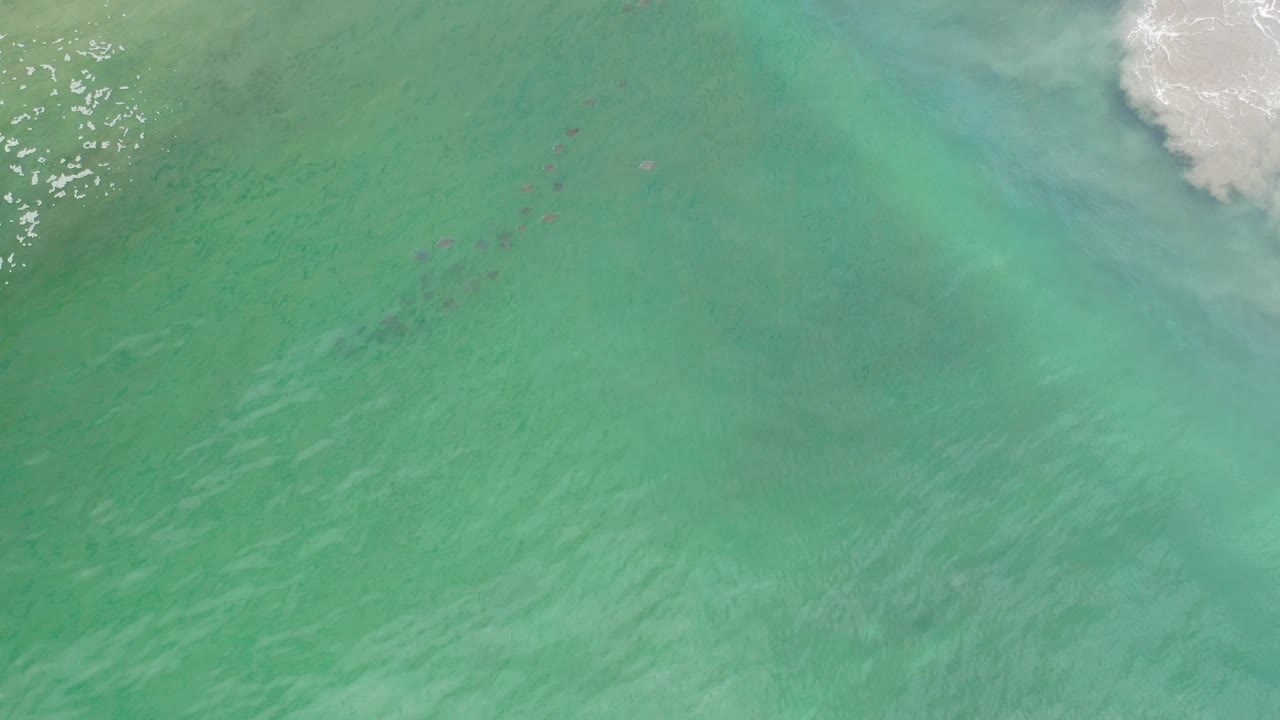 Rippling teal water with white foam at the upper right and darker streaks below.