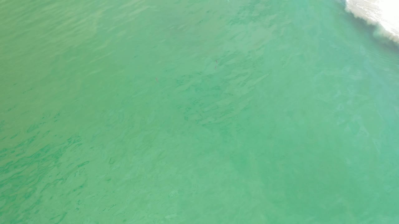 Turquoise-green water with a small white foam strip at the top right.