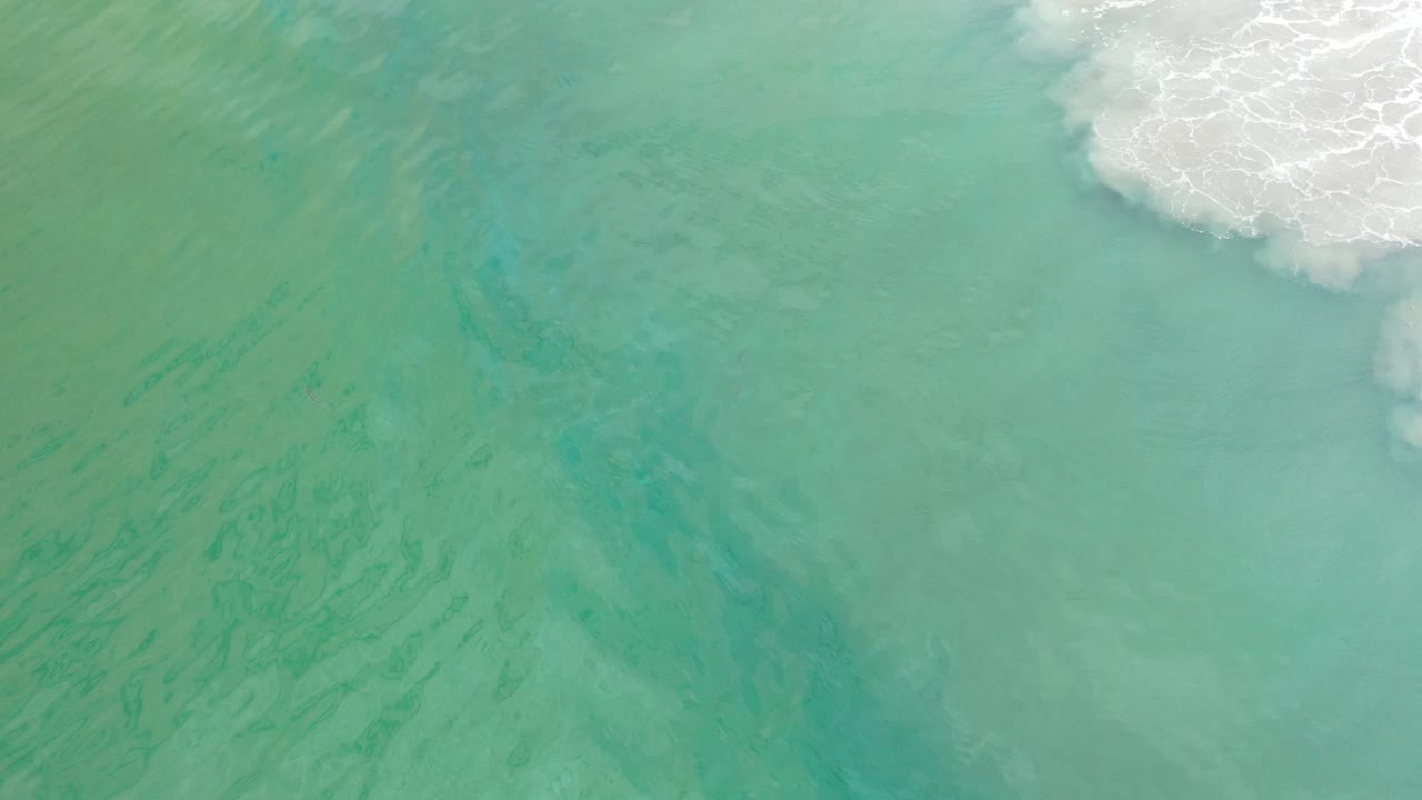 Turquoise green ocean water with white surf at the upper right.