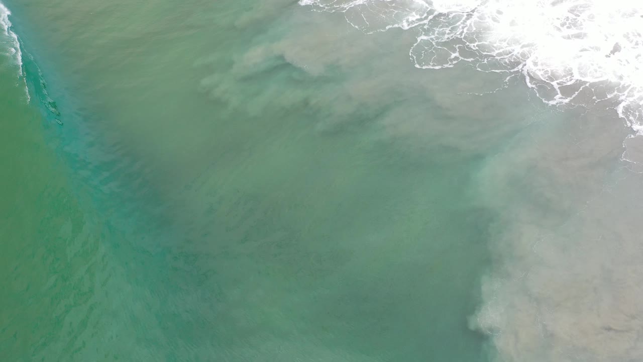 Turquoise water with a narrow darker channel beside breaking surf.