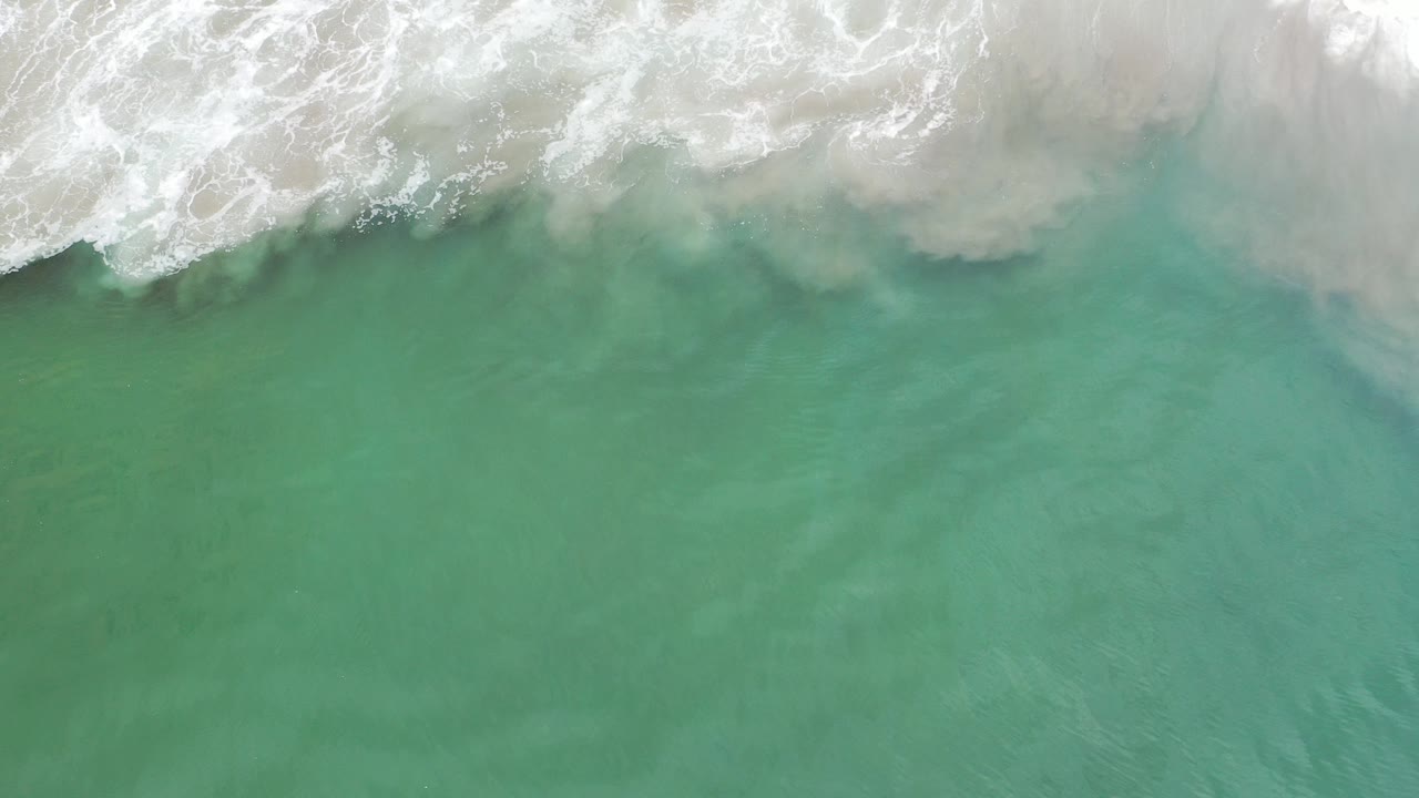 Overhead turquoise ocean water with white surf at the top edge