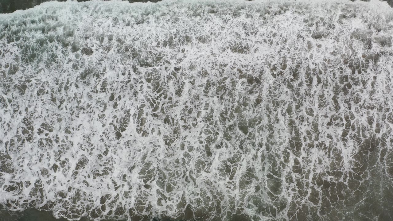 White foam advancing over shallow green water