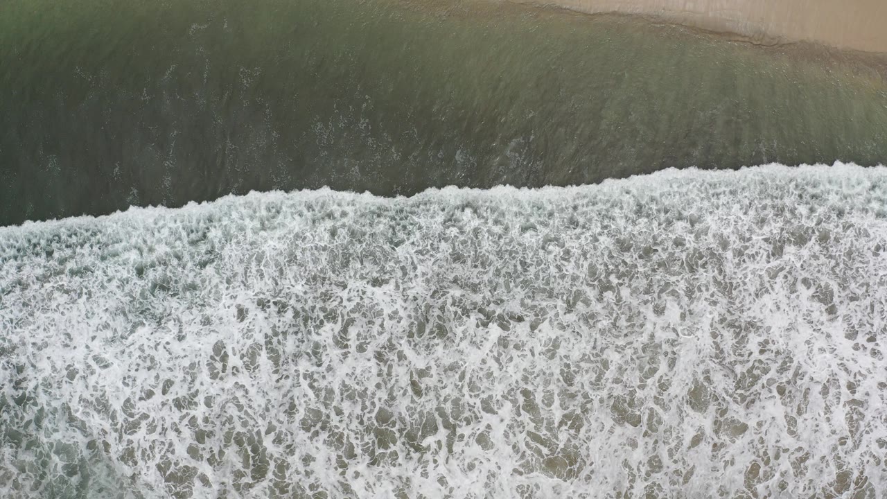 Overhead surf breaking onto a sandy beach
