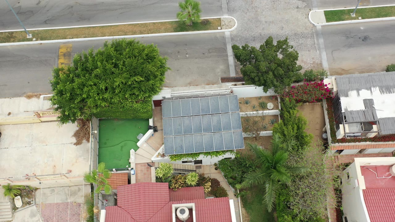 Overhead view of rooftops, trees, a green water feature, and a road.