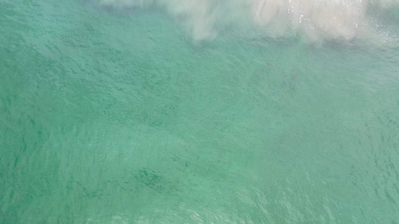 Turquoise water with surf foam crossing the top of frame.