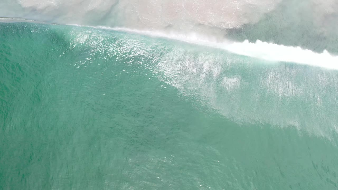 Aerial view of Los Cabos ocean water with the white surf band stretching across the top and no visible people.