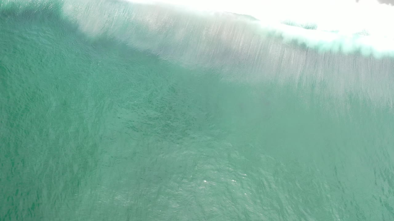 Close overhead view of a wave crest over green-blue ocean.