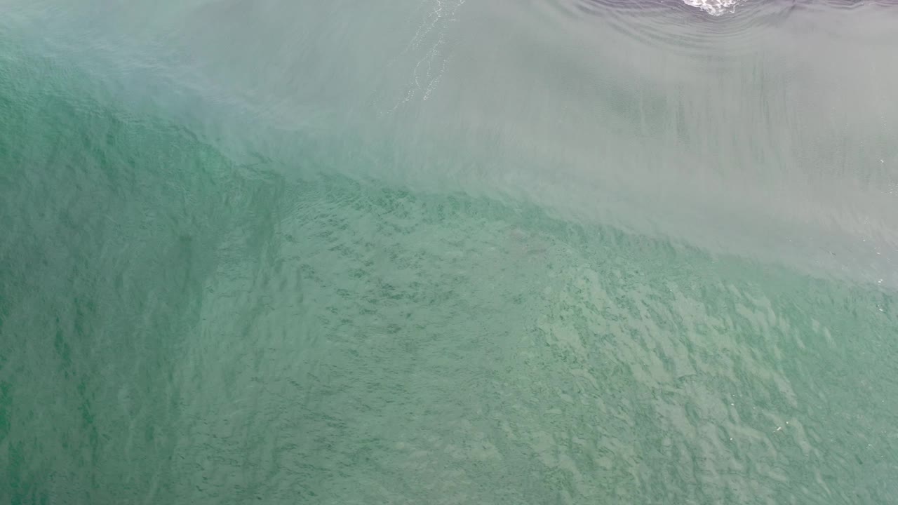 Aerial surf edge with green water and sand patterns