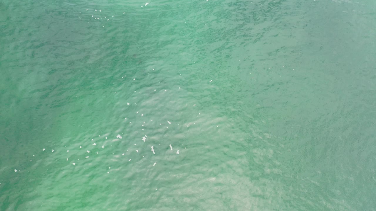 Top-down view of turquoise rippled seawater.